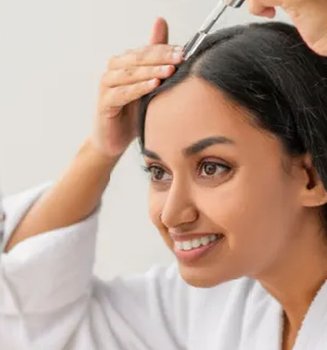 wanita dengan rambut tebal menggunakan serum untuk mencegah rambut rontok